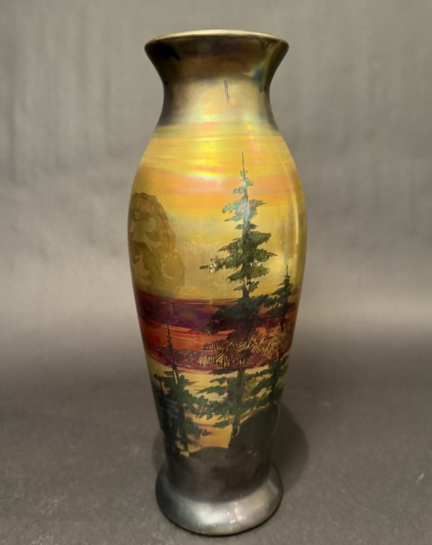 Weller Lasa Vase Landscape Scene: A Weller Lasa iridescent pottery scenic vase. Decorated with a lake bordered by mountains, tall pine trees in the foreground, in shades of red, orange, and bronze.Height 13.25". The Estate of the late
