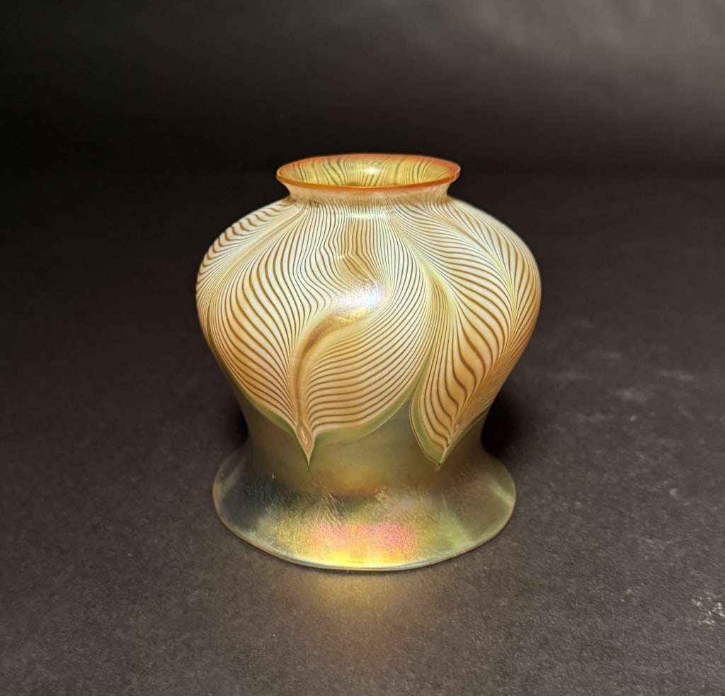 Quezal Iridescent Pulled Feather: Gold aurene interior. 4 1/2" H. 2 1/8" Fitter opening. The Estate of the late Judy Boyd, New Jersey.STERLING ASSOCIATES STRIVES TO PROVIDE ACCURATE, OBJECTIVE, & FAIR INFORMATION ON ALL LOTS. WE WILL 