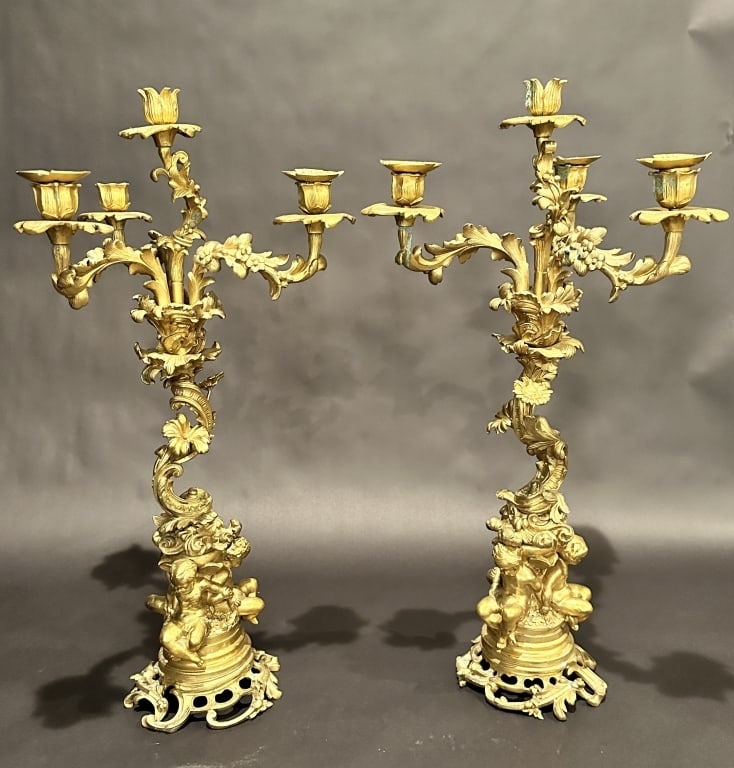 Pair Of Gilt Bronze Candelabra: Pair of gilt bronze Napoleon III candelabras withtwisted foliate center stem supported by winged angels at base.Surface verdigris.25" x 14"STERLING ASSOCIATES STRIVES TO PROVIDE ACCURATE, OBJECTIVE, &