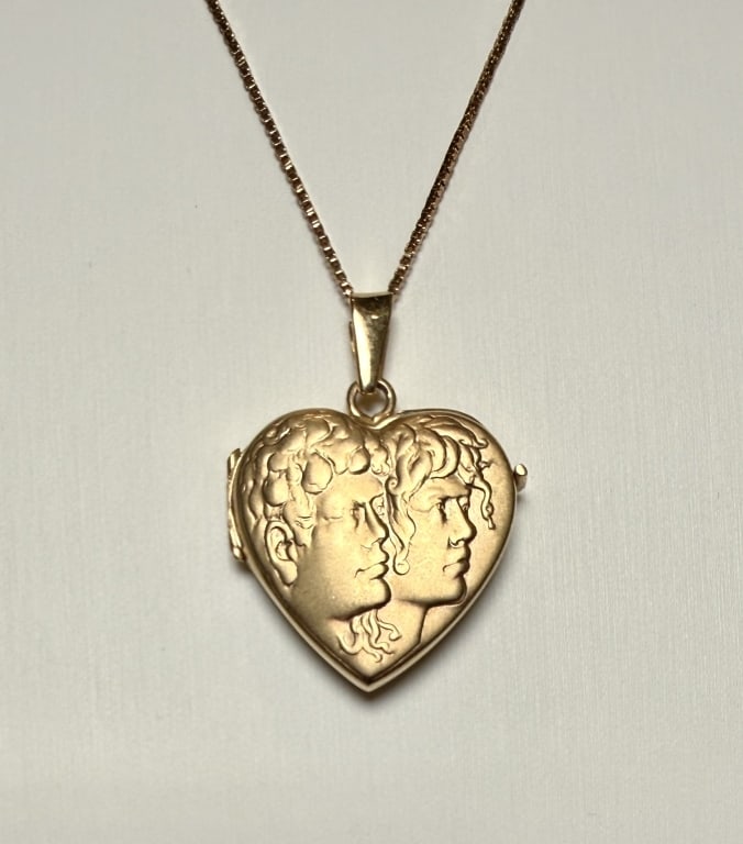 14K Gold Heart Locket Necklace: Embossed with image of young couple. Box link chain. Approx. dimensions including bail 1 3/8" x 1". Marked 14K.Approx. gross weight 9.7 grams. STERLING ASSOCIATES STRIVES TO PROVIDE ACCURATE, OBJECTIV