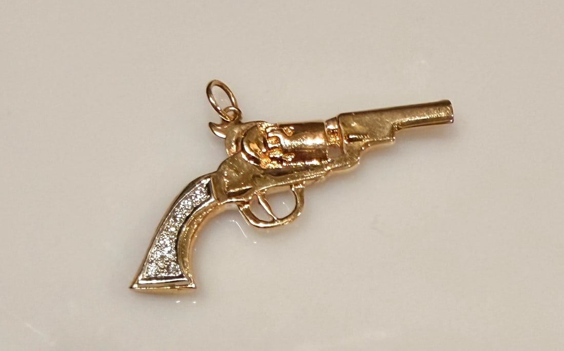 14K Gold And Diamond Pistol Form Pendant: Approx. dimensions 1 5/8" x 7/8". Tested 14K. Approx. gross weight 7.4 grams.STERLING ASSOCIATES STRIVES TO PROVIDE ACCURATE, OBJECTIVE, & FAIR INFORMATION ON ALL LOTS. WE WILL BE HAPPY TO ANSWER ANY 