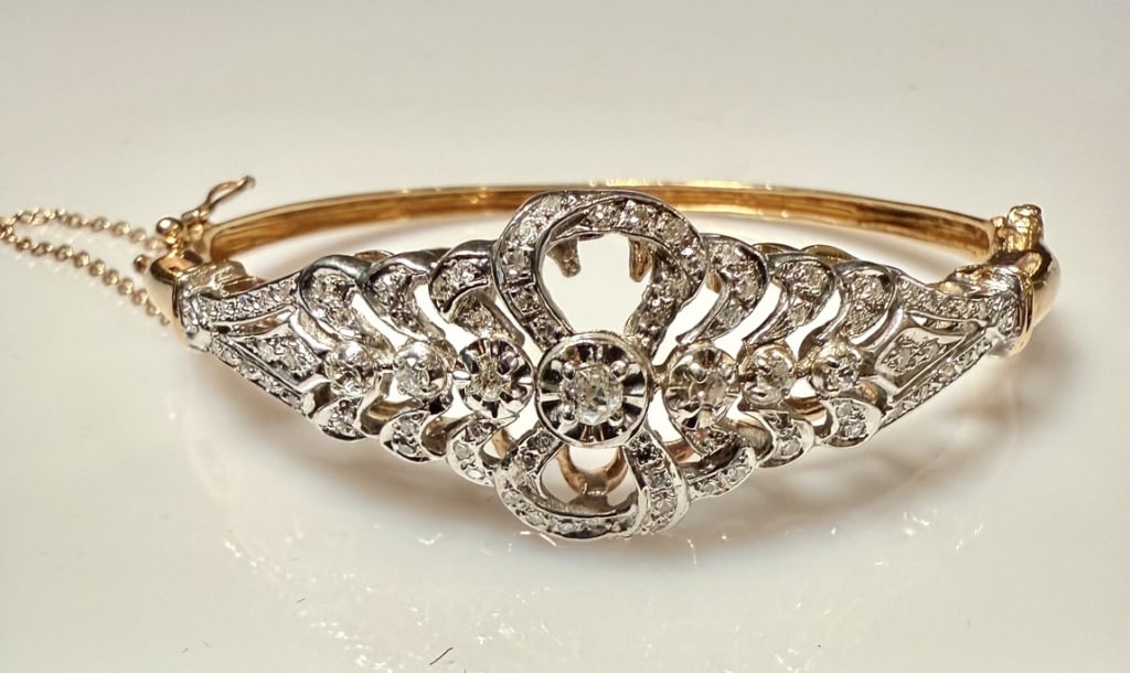 14K Gold And Diamond Bangle Bracelet: Yellow and white gold and diamond bow form bangle bracelet. 83 round diamonds(one missing) single cut approx. total carat weight 1.0cts. I Color. SI2 clarity.Tested 14K. Approx. gross weight 21.7 gram