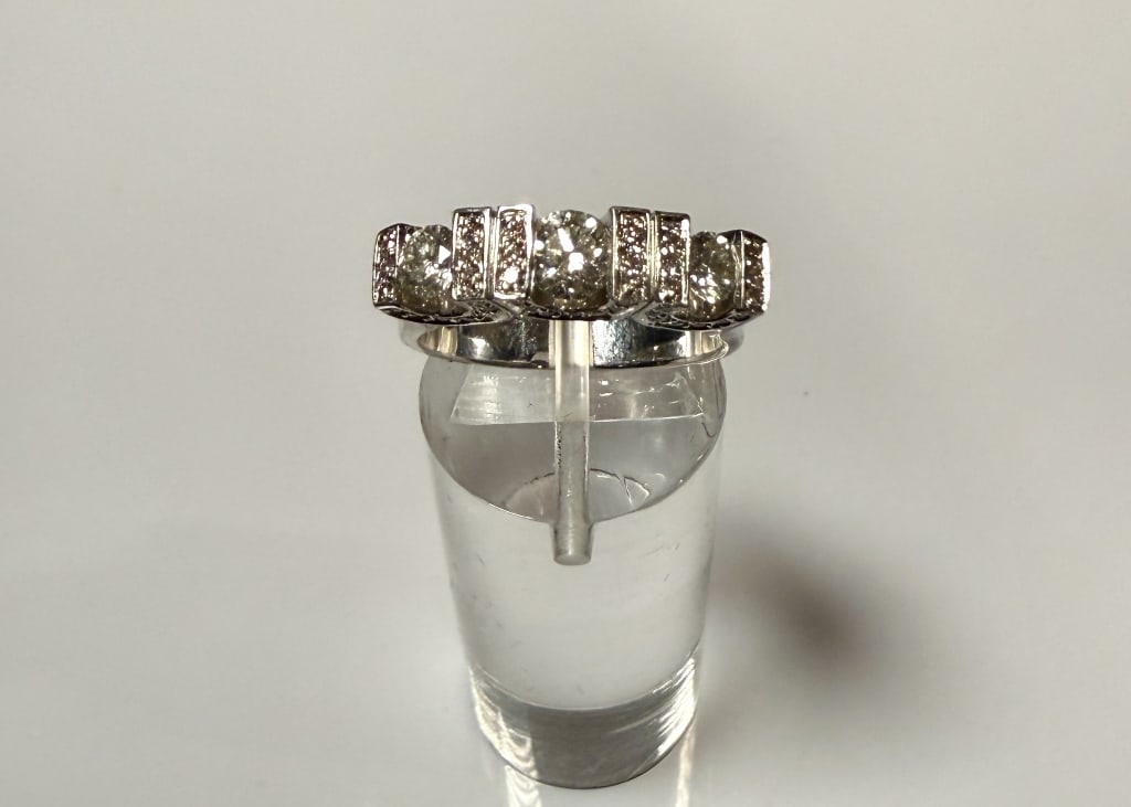 14K White Gold And Diamond Ring: 3 diamonds approx. 1.10 carats. J color. SI2 clarity. 62 small round diamonds on setting. Ring size 7 1/4 Marked 14K Approx. gross weight 7.0 grams. STERLING ASSOCIATES STRIVES TO PROVIDE ACCURATE, OB