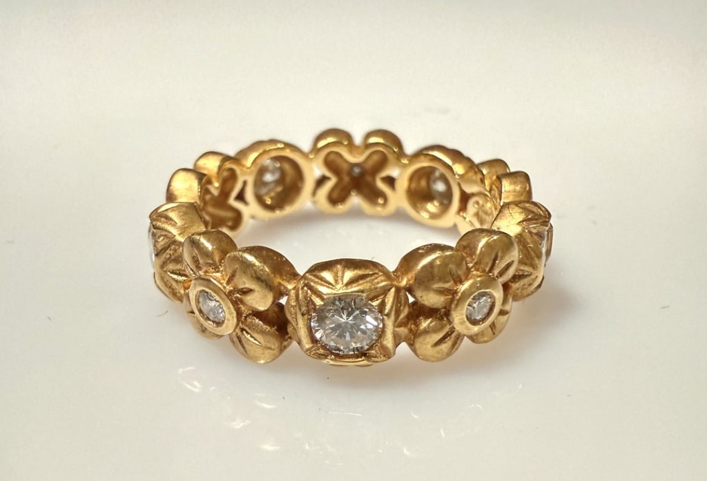 18K Gold And Diamond Eternity Band: Floral and geometric. Ring size 6 1/2. Marked 18K with makers mark. Approx. gross weight 7.3 grams. STERLING ASSOCIATES STRIVES TO PROVIDEACCURATE, OBJECTIVE, & FAIR INFORMATION ON ALL LOTS. WE WILL B