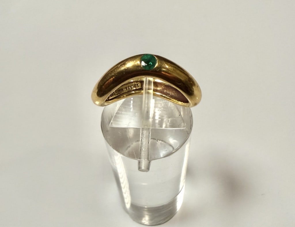 18K Gold And Emerald Twist Ring: 1985 Cummings. Ring size 4 1/2. Marked 18K and makers mark. Approx. gross weight 5.5 grams.STERLING ASSOCIATES STRIVES TO PROVIDE ACCURATE, OBJECTIVE, & FAIR INFORMATION ON ALL LOTS. WE WILL BE HAPPY