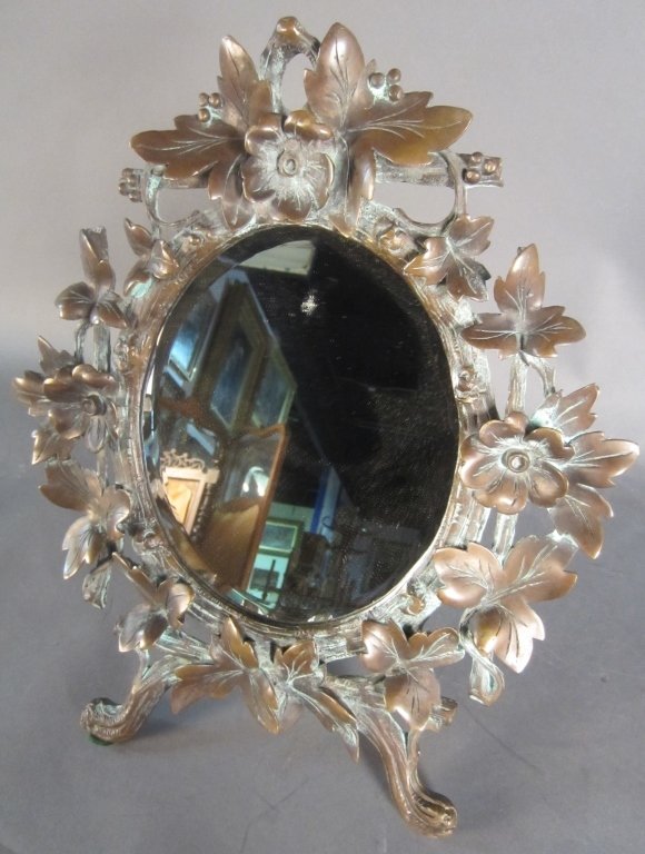 Mirror in Bronze Frame: Antique table top mirror in bronze floral frame. Height: 17 1/2", Width: 14 1/2"