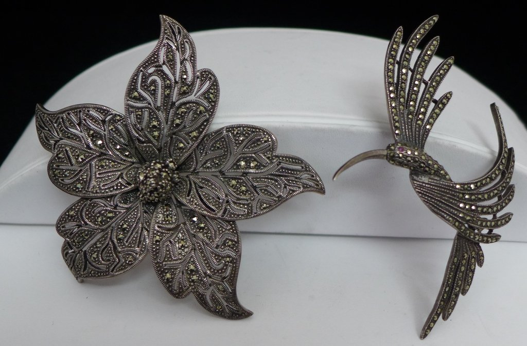 Two Sterling Silver and Marcasite Brooches: Two beautiful sterling silver and marcasite pins/ brooches. Height of flower brooch: 3", Width: 3", Height of hummingbird: 21/8", Width: 3". Approx total weight: 55 grams.