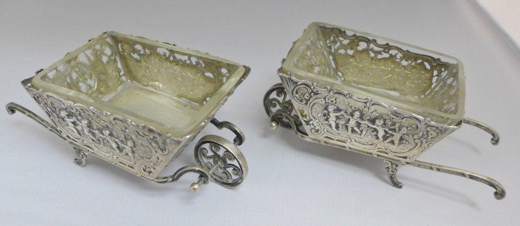 Pair of German Antique Silver Wheelbarrows: Pair 19th Century German silver & glass wheelbarrow novelty dishes. Beautifully pierced and decorated with a German Rococo style decoration of: scrolls, flowers and Putti. Both comes with their origin
