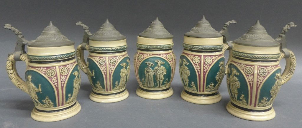 5 German Ceramic Beer Steins: Collection of 5 German pottery beer steins/ mugs with molded pewter lids. Numbered on the bottom. Height: 5 1/2", Width: 3 3/4"