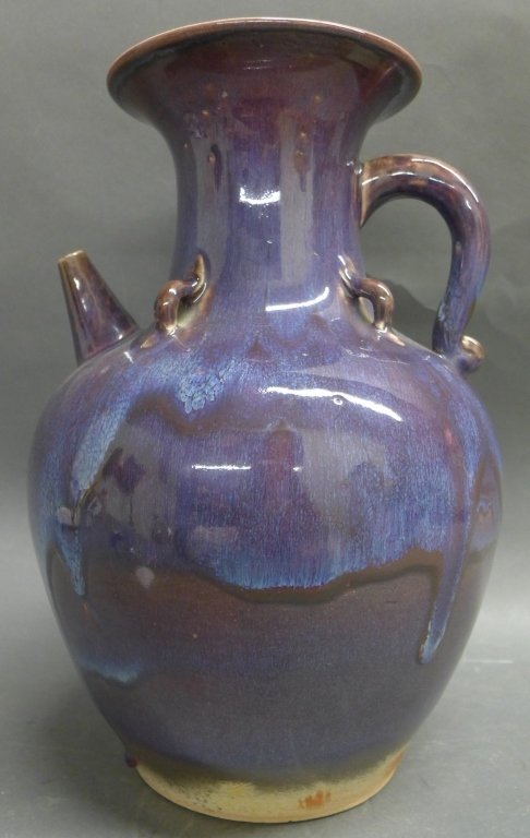 Flambe Glazed Pitcher: Flambe glazed earthenware pitcher with intense magentas, crimsons, and purples of the body glaze, accented with an undulating streak of sky blue glazed. Signed on bottom. Height: 12 1/2", Width: 8"