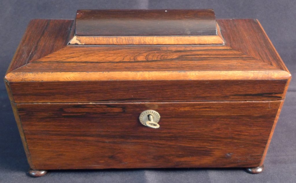 Victorian Rosewood Tea Caddy, 19th C: Antique English rosewood tea caddy. This hinged box has the original lock and key, which was used to prevent the household staff from stealing the expensive tea at the time. On 4 bun feet. Some damage