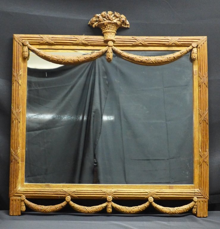 Large Mirror in Carved Wood Frame: Vintage mirror in hand carved wood frame. Carved elements include: flowers, basket, draping swags of garland, and tassels. 1 tassel is loose. Slight scratches on mirror and wear to wood. Height: 36", 