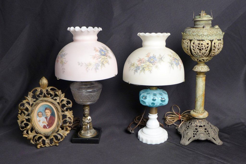 Group of Victorian Lamps and Picture Frame: Group of three American Victorian tabletop lamps and one brass picture frame. Included in this collection is one banquet lamp with brass and onyx base (missing globe). Two pressed glass lamps, each el