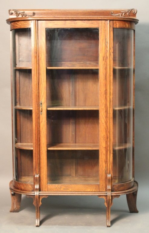 Antique Curved Glass Vitrine: Antique glass display cabinet with curved glass sides. The cabinet has flat cornice and simply decorated back apron over large glass front door base. Three interior shelves are designed with plate gro
