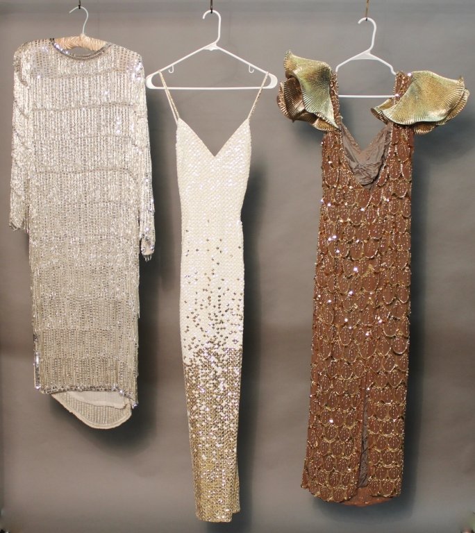 Assortment of Vintage Gowns: Collection of three vintage gowns. Including: one sequin and beaded gown with pleated sleeves. Dim. laying flat: Waist: 14 1/2"; Length: 54" . One silver sequin and beaded fringe dress with beautiful 