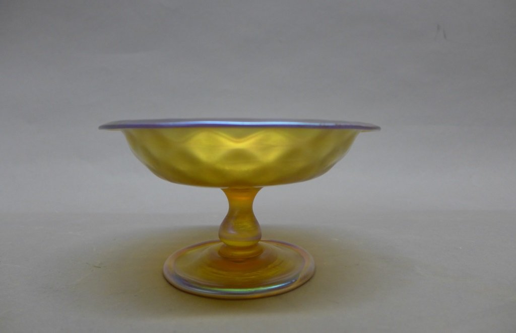 Tiffany & Co Favrile Compote: Beautiful gold iridescent Tiffany Studios compote. Diamond shaped texture "quilted" top bowl on pedestal base. Marked on bottom: L.C. Tiffany Favrile 1912. Height: 3 3/8", Diameter: 6 1/8" (studio gla