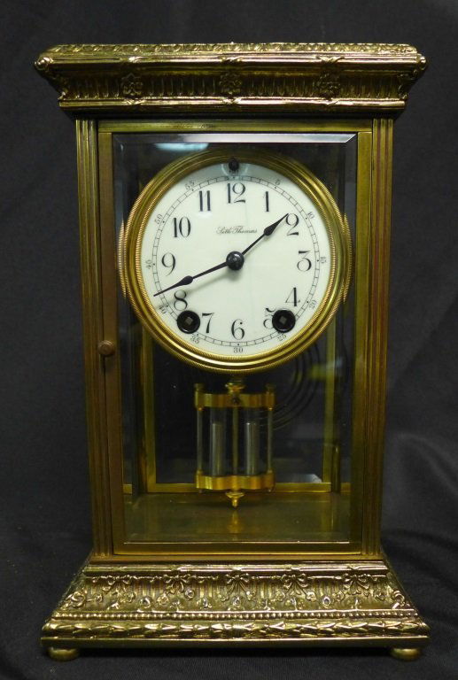 Seth Thomas Regulator Clock: American made brass and beveled glass regulator clock with mercury pendulum by Seth Thomas. Ornate design on top and base of clock. Face of clock reads: Seth Thomas. Back of clock is stamped: ST USA 4