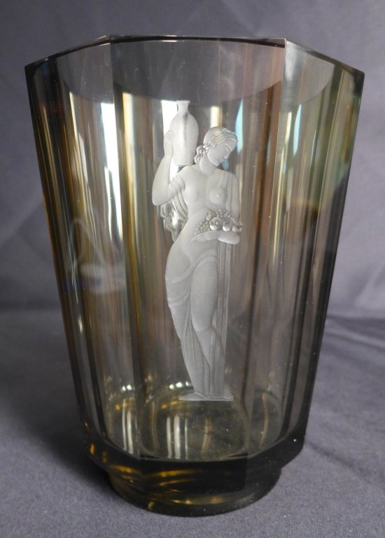 Large Vicke Lindstrand for Orrefors Vase: Absolutely stunning art glass vase with hand cut and etched figural design depicting a Grecian woman holding a wine jug and fruit. Translucent topaz glass. Imperfections. Height: 8 1/2", Width: 6 1/4"