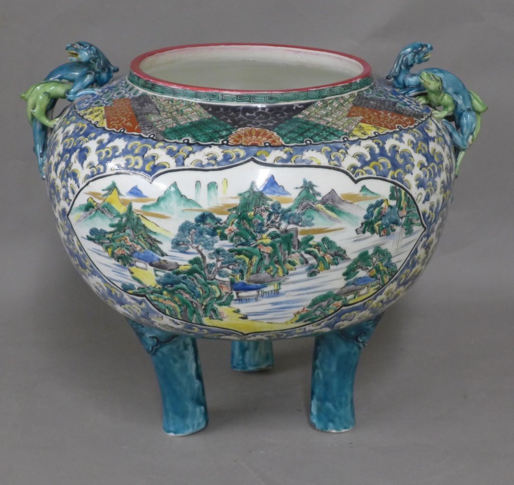 Large Kutani Footed Porcelain Bowl: Antique hand painted and gilt Japanese kutani porcelain bowl with dragons as handles. Tripod feet and figural scene painted on front. 1 chipped wing. Some firing imperfections and wear to surface. Mak