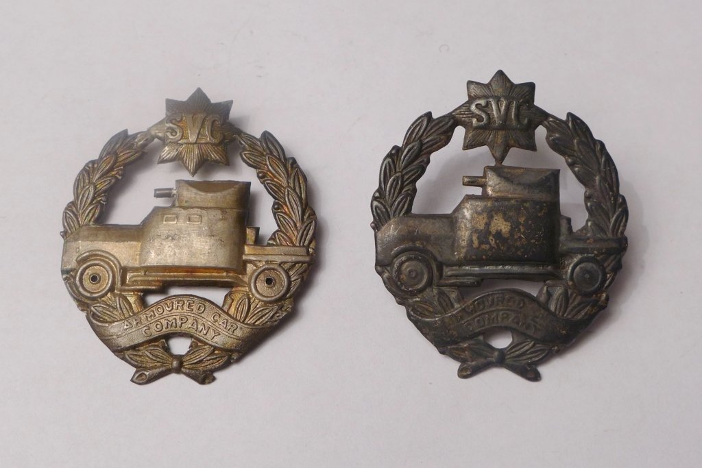 Pair of Armoured Car Company S.V.C. Badges: Very rare pair of Armoured Car Company Shanghai Volunteer Corp. cap badges. Design featuring olive tree leaves around armored car with eight point SVC star at the top and " Armoured Car Company" ribbo