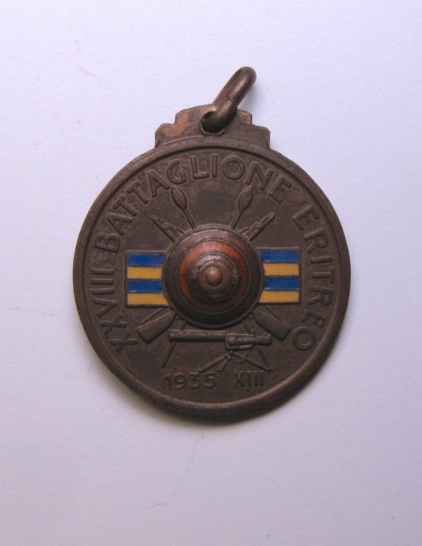 Italian Medal 28th Battalion Eritrea Africa: Italian Medal 28th Colonial Battalion Eritrea Africa. The obverse is depicting a shield with crossed weapons and blue and yellow enameled stripes, signed " XXVIII Battaglione Eritreo/ 1935 XIII". The 