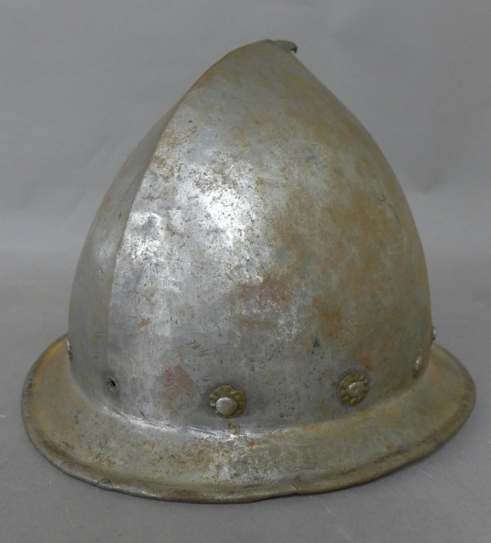 16th Century Spanish Morion Helmet: Antique Spanish iron Cabacete Morion helmet with decorative/ riveted rosettes around base and small point protruding from the crown. Hallmark on back of turned-down brim. Noticeable age and wear. Heig