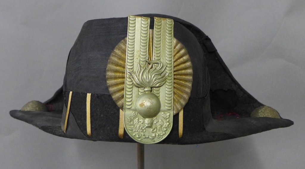 French Foreign Legion Bicorne Hat: Vintage military bicorne hat with Grenade insignia depicting hand grenade with a rising flame. Maker's label on inside brown leather band. Some age appropriate wear. Height: 6", Width: 16 1/2", Depth:
