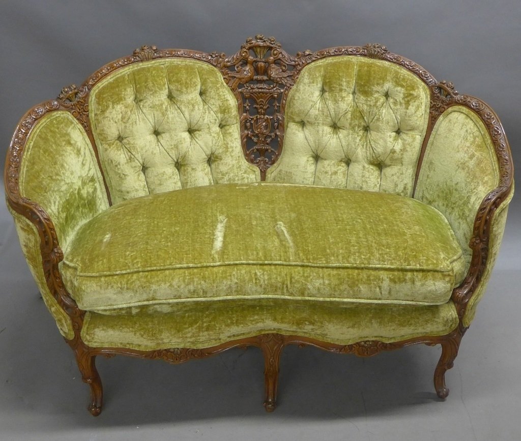 Beautifully Carved & Upholstered Settee: Light green Victorian upholstered settee with tufted back. Ornate carved wood frame has bird detail in center. Rests on 6 legs. Some wear and slight discoloration. Height: 37", Width: 56", Depth: 27" 