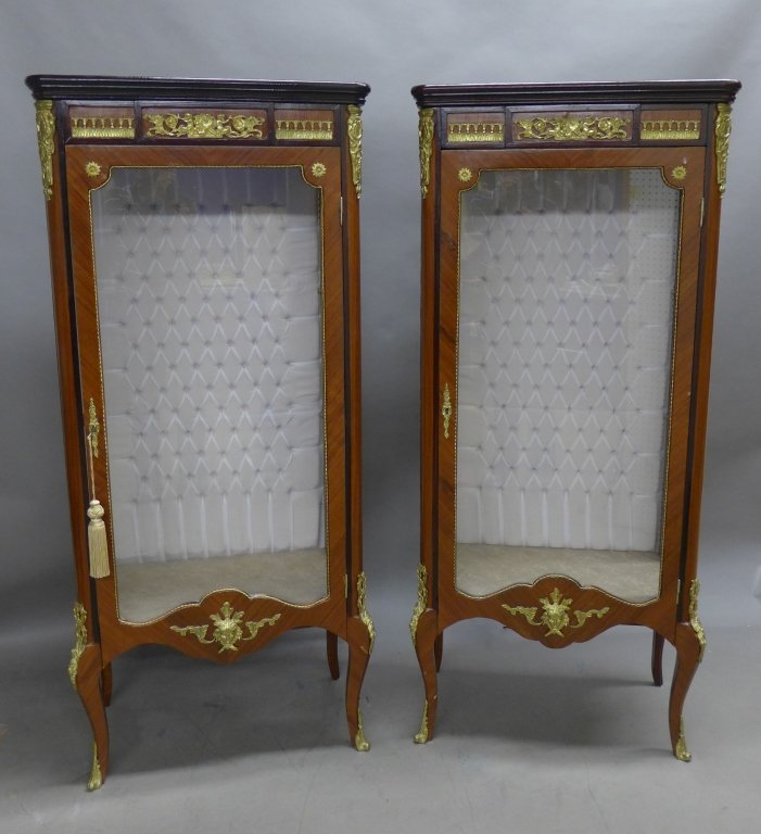 Pair Bronze Mounted Vitrine Cabinets: Lovely pair transitional Louis XV & XVI style vitrines with cabriole legs. Figural and floral bronze mounts. Tufted back wall and upholstered bottom liner depicting angels. 1 key. Some noticeable impe