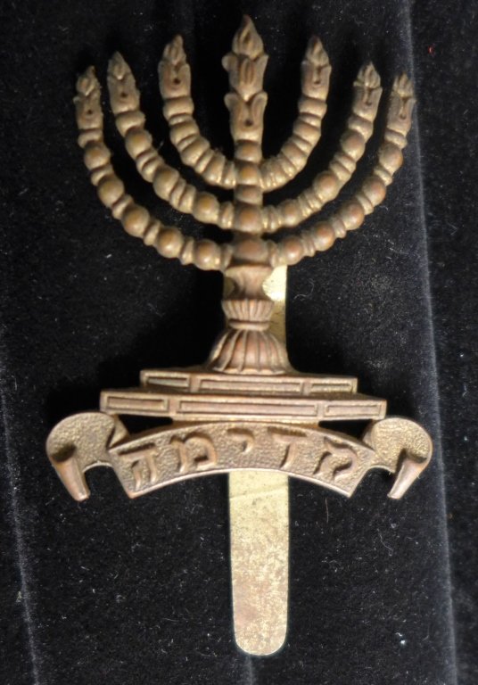 WWI Jewish Legion Cap Badge - Menorah: WWI Jewish Legion Cap Badge - Menorah. From the collection of Gene Christian. Height: 2 1/8" ; Width: 1 3/8". Age appropriate wear. STERLING ASSOCIATES STRIVES TO PROVIDE ACCURATE, OBJECTIVE, & FAIR I