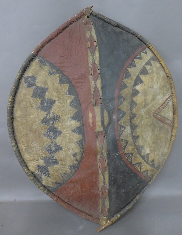 African Maasai Shield: Maasai shield is made of cattle hide stretched over and sewn on to a wooden frame with leather strips. It has a handle attached across the center at the back. Decorated with unique black, white and re