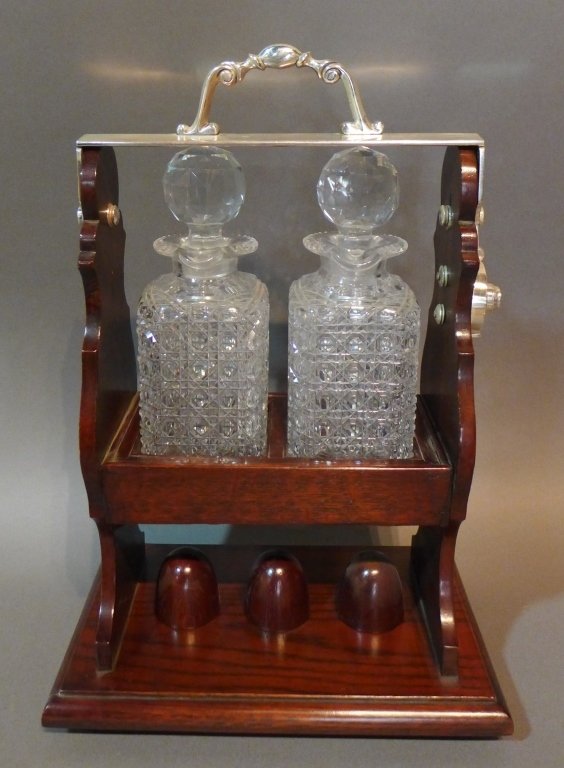 English Liquor Valet: Silver over bronze and oak liquor valet with 2 cut glass decanters with stoppers. Tiny chips on vessels. Maker's marks on both sides of handle, reads: Betjemann's Patent London 16201 & The Tantalus. 3