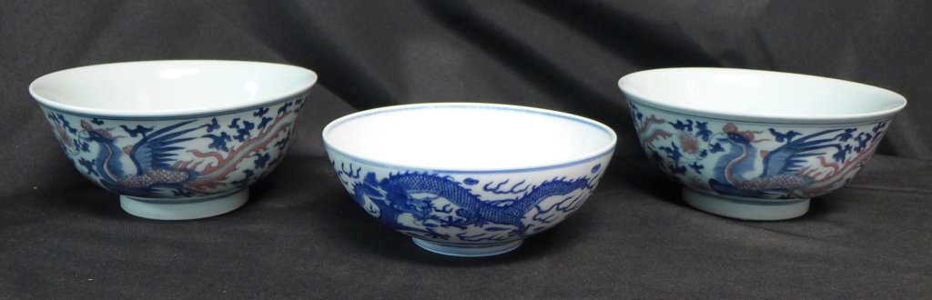 Collection of Blue and White Chinese Porcelain: Pair Asian blue and white phoenix bowls and one dragon bowl with crack. Dragon bowl is signed/ maker's mark on bottom. Both phoenix bowls have red design accents. All three bowls are hand painted and 