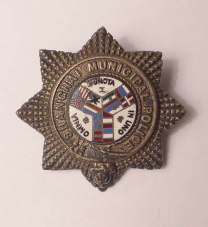 Silver Badge of the Shanghai Municipal Police: Rare silver badge of the Shanghai Municipal Police. Featuring white enamel background incorporating flags of all nations. Stamped hallmarks on the back._x000D_ Imperfections. Height: 1 5/8", Diameter: