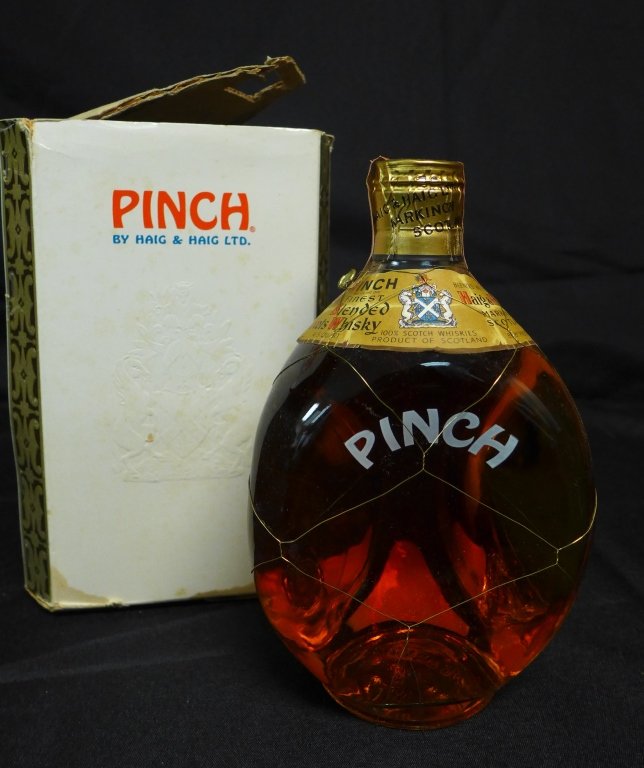 Pinch Scotch by Haig & Haig: Old triangular bottle of Haig & Haig Ltd, PINCH. Gilt wire mesh around bottle and the seal has not been broken. 86.8 proof. In original box. Height of bottle: 8", Height of box: 8 1/2" (Scotland, spir