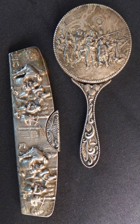 Antique Comb and Mirror Set: Victorian hand mirror and comb set. Mirror handle has floral motif. Turtle Shell comb has stylized floral decorative accent. Intricate chased and repousse figural design depicting colonial scenes on b