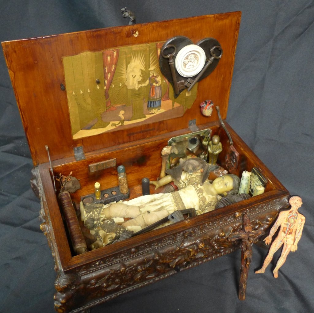 Voodoo Priestess Kit: 19th Century Voodoo kit in ornate wooden box. Possibly belonging to Voodoo Priestess Marie Laveau or one of her disciples. Includes wax doll, taxidermy bat, bone, cross, candles, antique spiritual boo