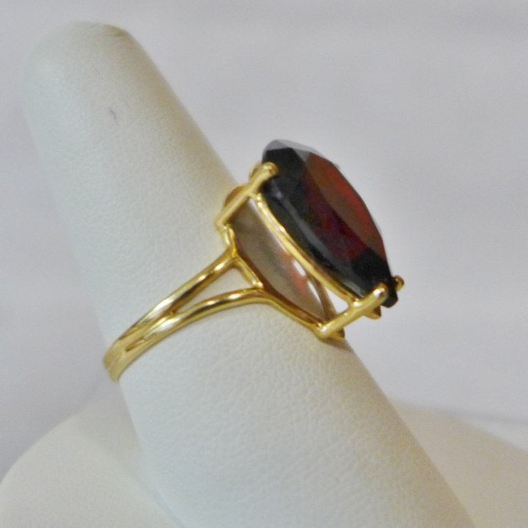 Pear Cut Garnet and Gold Ring: Pear Shape Garnet Ring With a Split Shank Band in 14K Yellow Gold, Band marked "14K / NISSKO". Ring size: 8. Height: 1"; Width: 3 /4"; Depth: 5/8". Total weight: 4 grams. STERLING ASSOCIATES STRIVES T