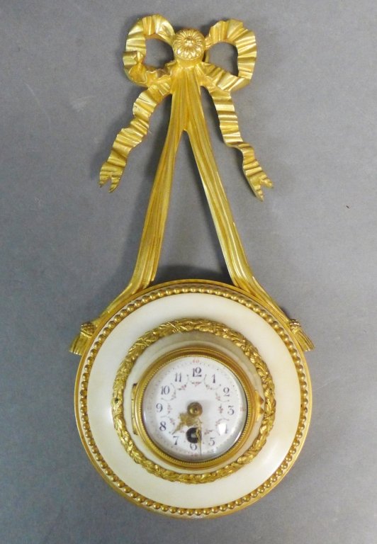 French White Marble & Gilt Bronze Cartel Clock: Beautiful antique hanging wall clock with gilt bronze bow stem and marble body. Louis XVI style. Enamel clock face is decorated with floral garland motif. Height: 11 1/2", Width: 5 1/2", Depth: 2" (ti