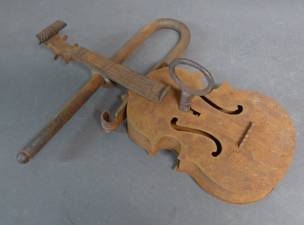 Large Figural Gate Lock in the form of a Violin: Functional gate lock and key in the shape of a violin or cello. The iron has a beautiful rust patina and chiseled floral design. Height: 14 1/2", Width: 12 1/2", Depth: 2 1/2" (craftsmanship, metal wo