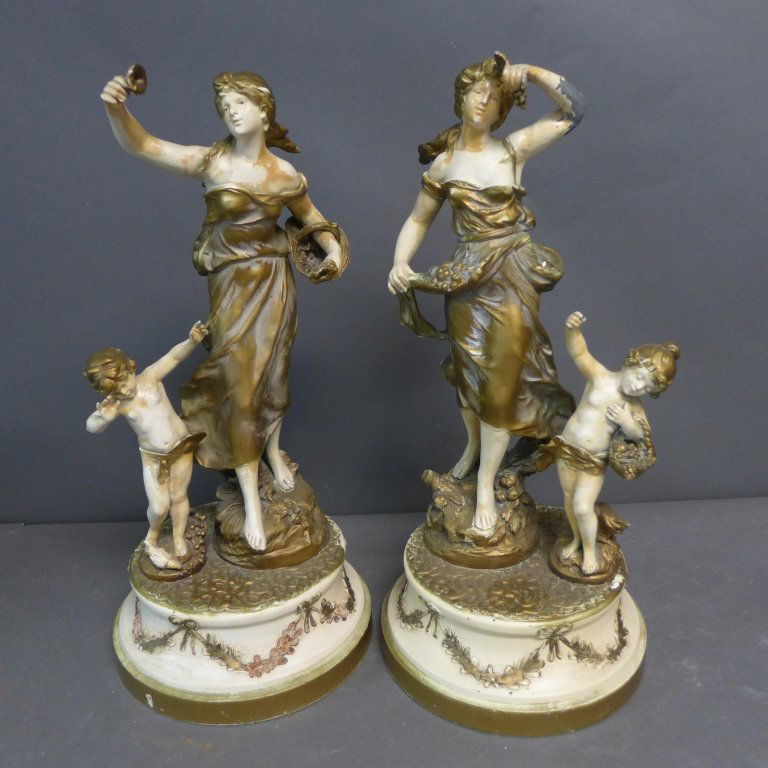 Pair Figural Spelter Statues: Two cold painted figural sculptures on round bases. Both pieces depict an elegant woman with a child at her side. Artist signature incised on both: Auguste Moreau. Paris Foundry mark on both as well.