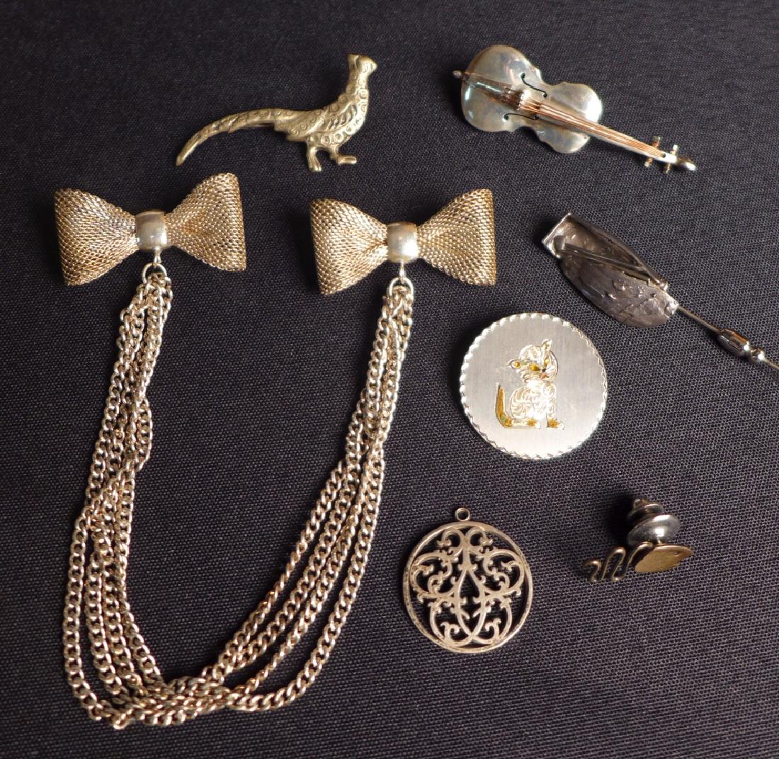 Assorted Silver Brooches and More: Seven assorted sterling silver pins, brooches and more. Includes a violin, pheasant, cat, fish and more. Makers marks. Total approximate weight: 55 grams. Bow tie pin: Length: 9"; Width: 1 1/2". STERL