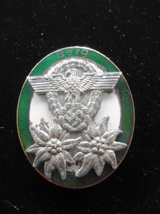 WW II German Nazi Enamelled Mountain Garde Badge: WW II German Nazi Mountain Garde Badge with eagle swastika and edelweiss. Green enamel around edge with "Berg" on the top. White enamel center. Back clasp is intact. Marking on back reads "Deschler &