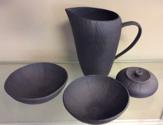 Michael Aram Mid Century Pottery Grouping: Matte black set includes a water pitcher, covered bowl and 2 round bowls.Marked: On bottomDimensions: Pitcher: 9" (H); Covered bowl: 5" (D) x 2" (H); Bowls: 6 5/8" (D) x 2 1/4" (H).Condition: Very goo