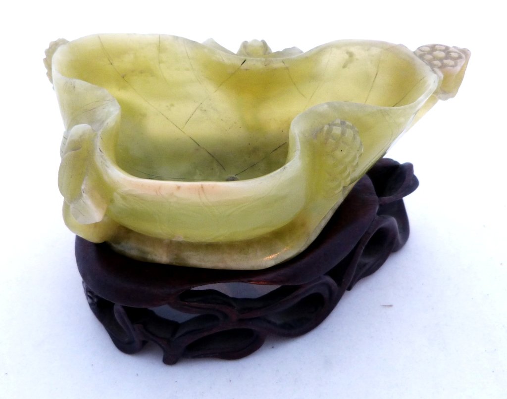 Jade Chinese Antique Bowl on Stand: Chinese antique jade, Abstract shaped bowl with floral carvings, on a wooden incised base.