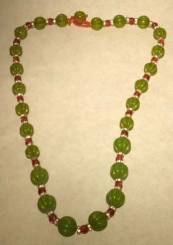 Vintage Trifari Carved Bakelite & Rhinestone Necklace: beautiful possible old trifari carved bakelite green beads with red bakelite beads as clasp and rhinestone rondelles.not marked good condition