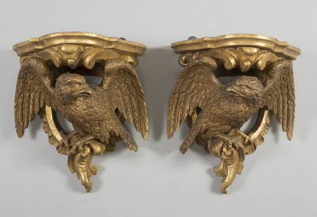 A PAIR OF CLASSICAL GILT & GESSOED WHITE PINE EAGLE: The eagles with spread wings and gazing at each other, perched upon ruffled c-scrolls, with leafage. Appear to retain the original gilding, with minor touch-ups over time.Based on Harry Aldens