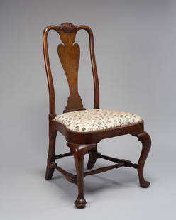 QUEEN ANNE SHELL-CARVED BALLOON-SEAT WALNUT SIDE CHAIR: The shell-carved crest rail above rounded stiles flanking a vasiform splat with deeply cut shoulders, the slip-in compass seat and seat rail, supported by cabriole legs, all joined by arrow-turned