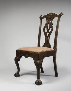 CHIPPENDALE SHELL AND VOLUTE-CARVED MAHOGANY SIDE CHAIR: The crest rail with scrolled-back ears with tassels with emanate towards the center with volutes above a central shell, with a volute-carved pierced-splat flanked by fluted styles. The slip-in seat