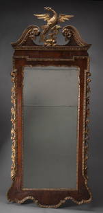 GEORGIAN WALNUT VENEERED AND GILTWOOD LOOKING GLASS: Monumental Georgian walnut veneered looking glass. The glass in two parts, enclosed by a walnut-veneered frame with gilt and gessoed phoenix. The lower frame with cyma-shaped gilt